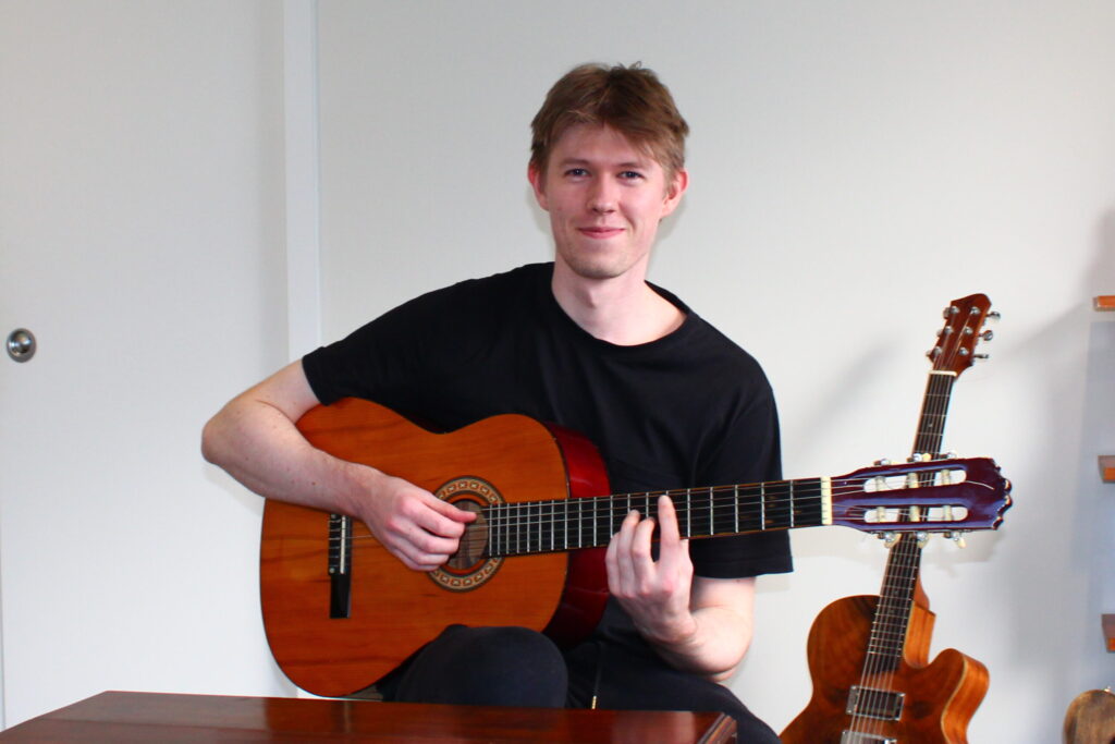Smiling guitar teacher playing acoustic guitar.